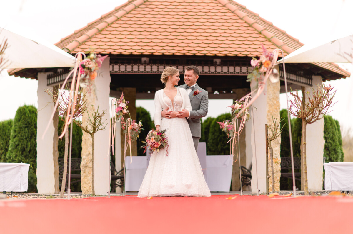 Ein Brautpaar steht vor einem Pavillon.