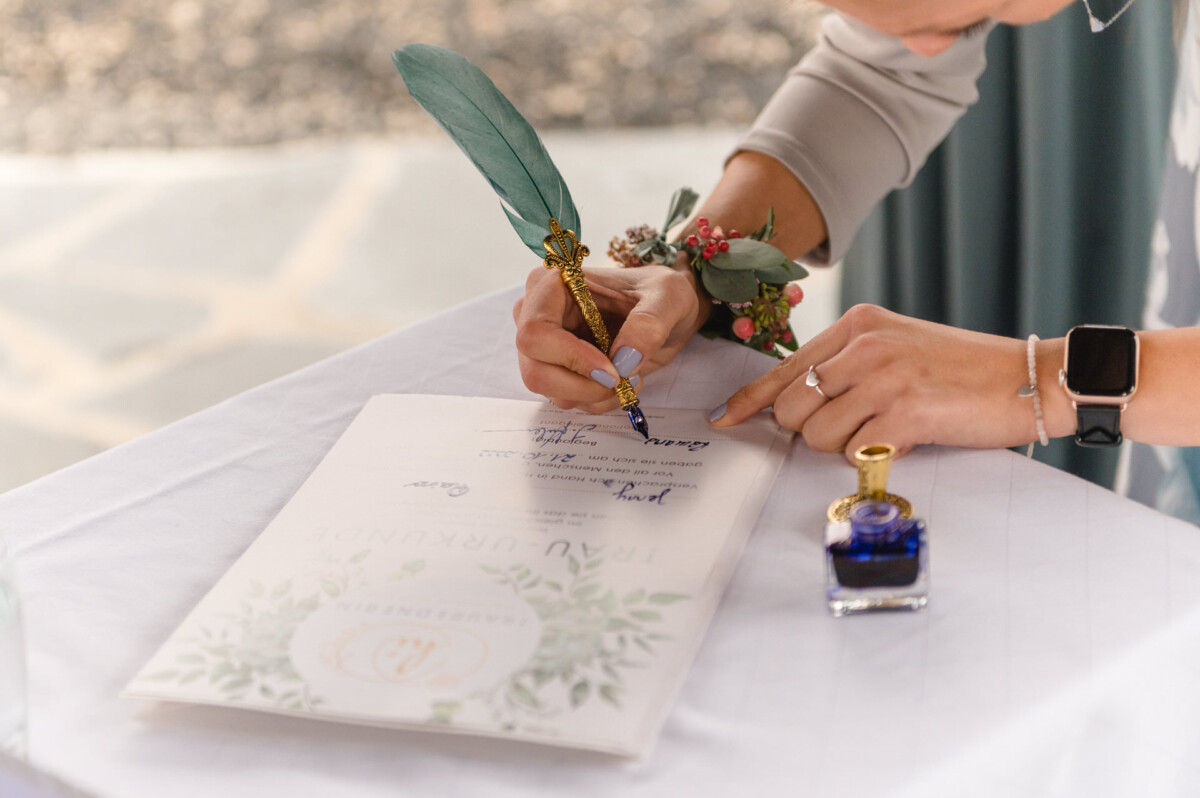 eine Frau, die eine Hochzeitskarte mit einem Federkiel unterschreibt.