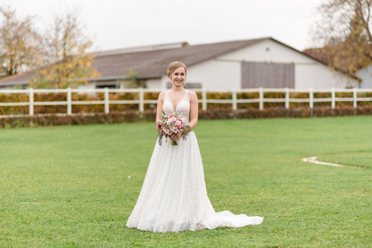 eine Frau in einem Hochzeitskleid, die im Gras steht.