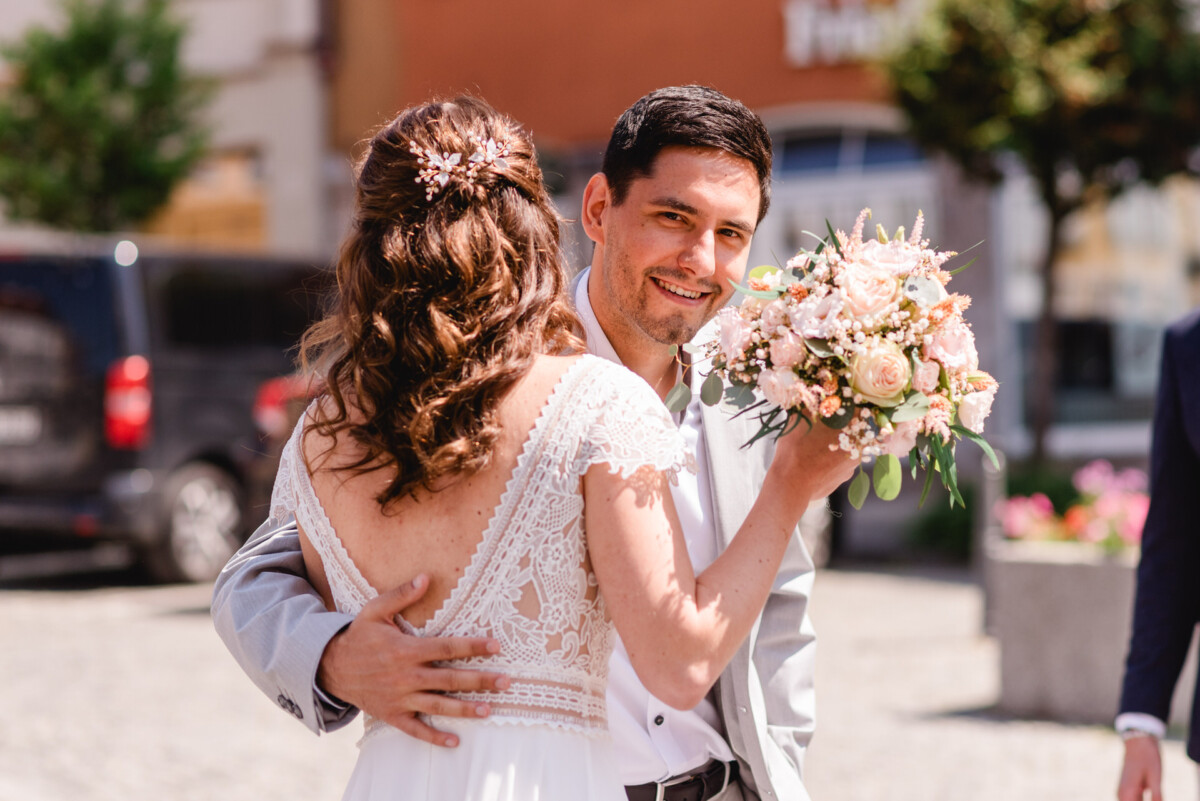 Eine Braut und ein Bräutigam umarmen sich, während sie die Straße entlang gehen.