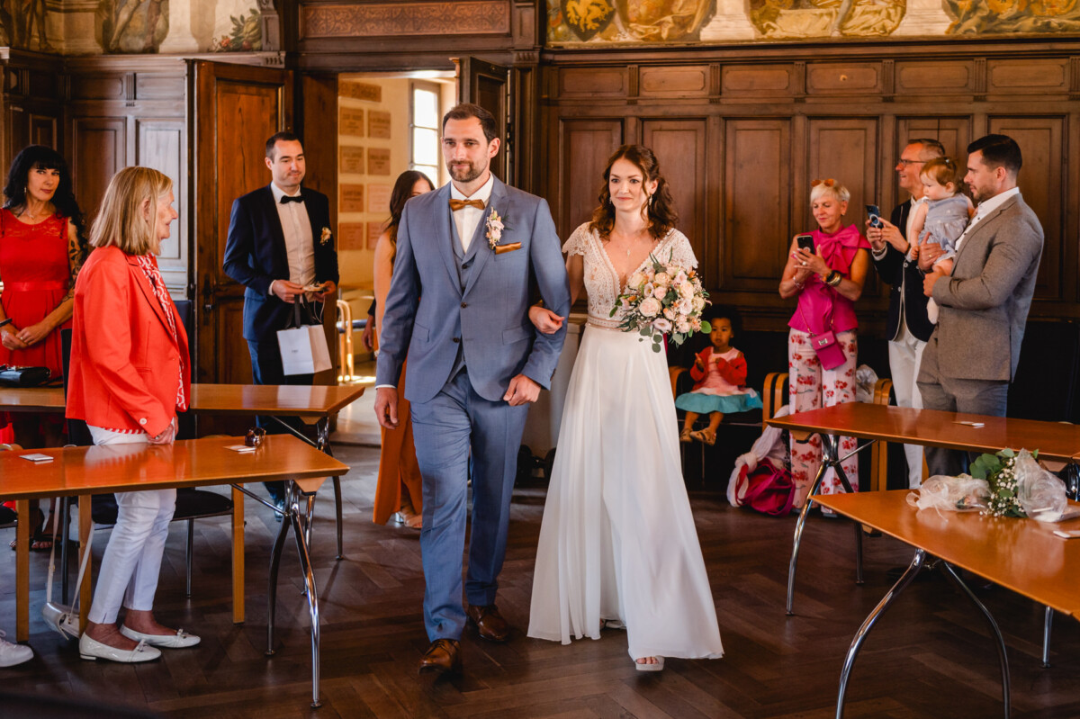 Eine Braut und ein Bräutigam gehen bei einer Hochzeitszeremonie den Gang entlang.