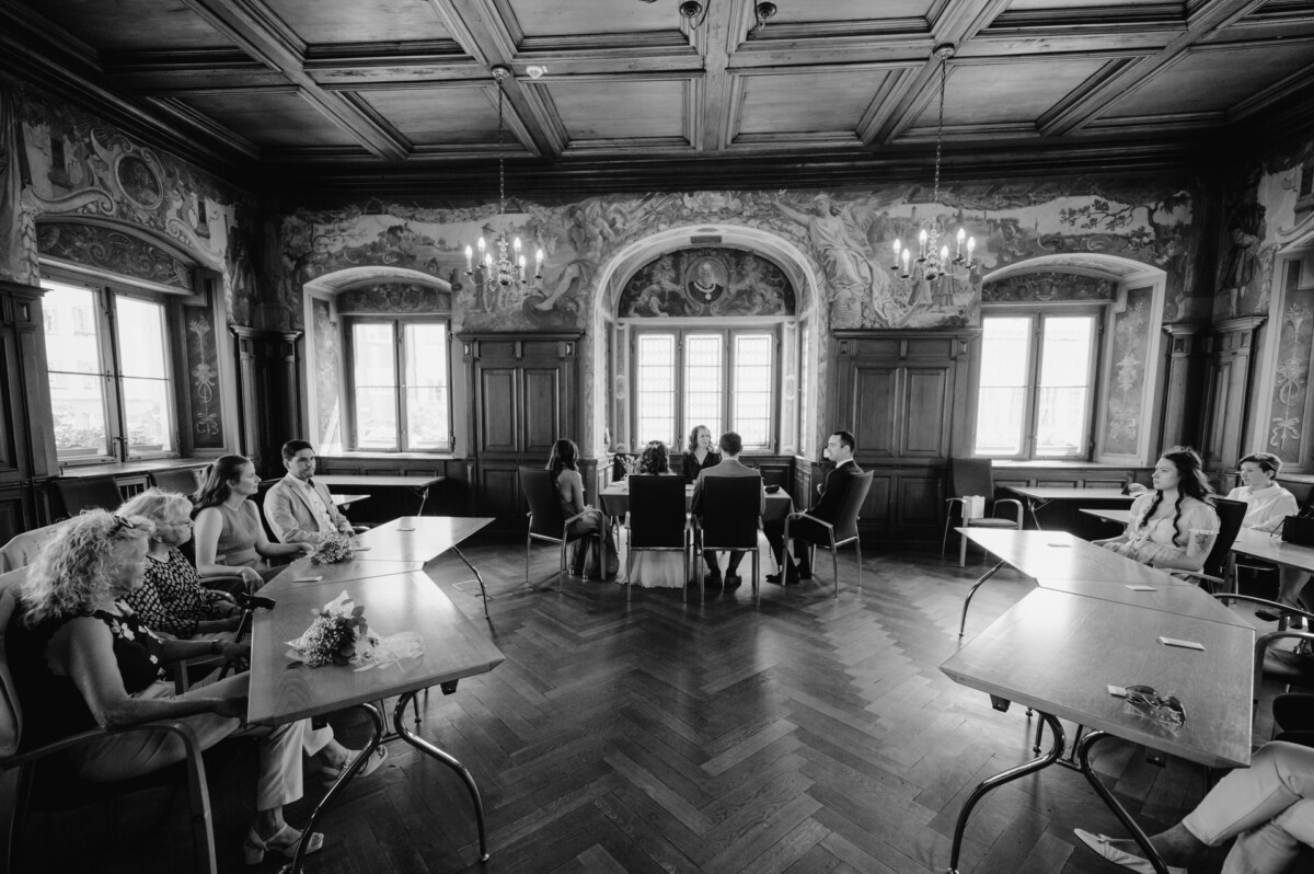 Ein Schwarz-Weiß-Foto einer Gruppe von Menschen, die an einem Tisch sitzen.