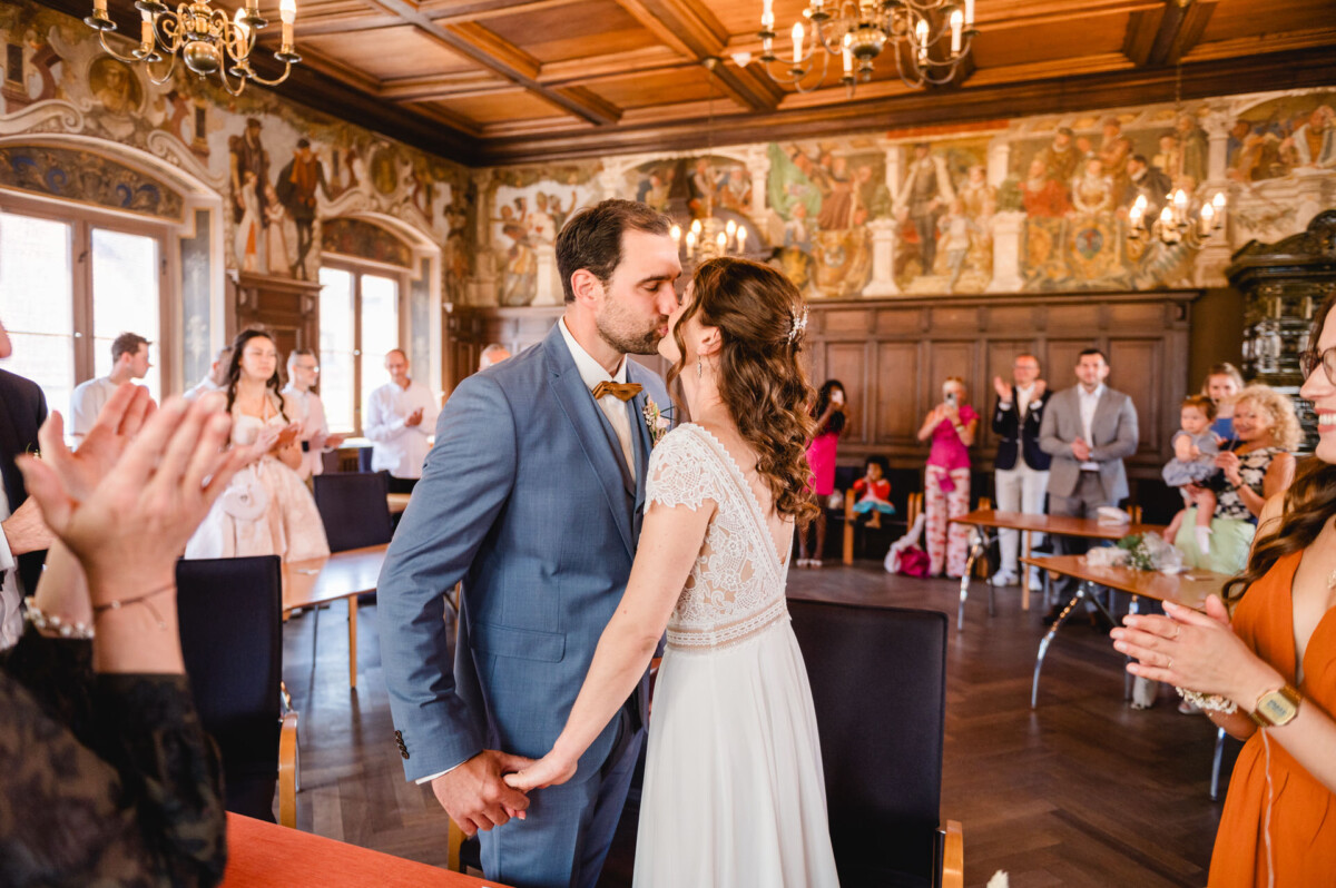 Ein Brautpaar küsst sich vor einer Menschenmenge.