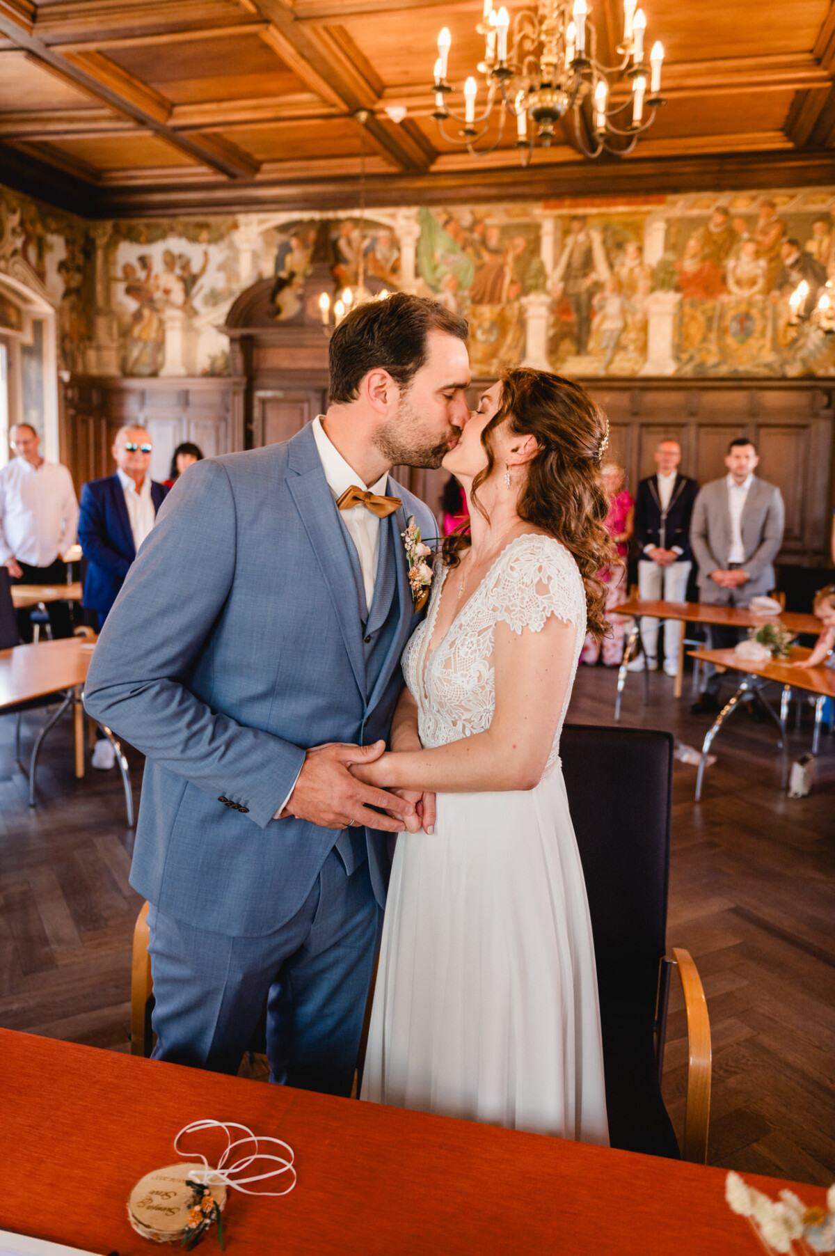Eine Braut und ein Bräutigam küssen sich vor einem reich verzierten Raum.