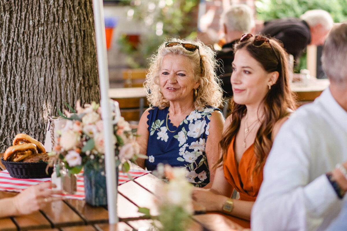 Eine Gruppe von Menschen sitzt bei einer Veranstaltung im Freien um einen Tisch.