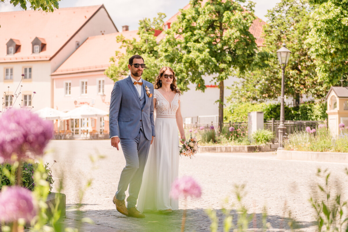 Eine Braut und ein Bräutigam gehen eine gepflasterte Straße entlang.