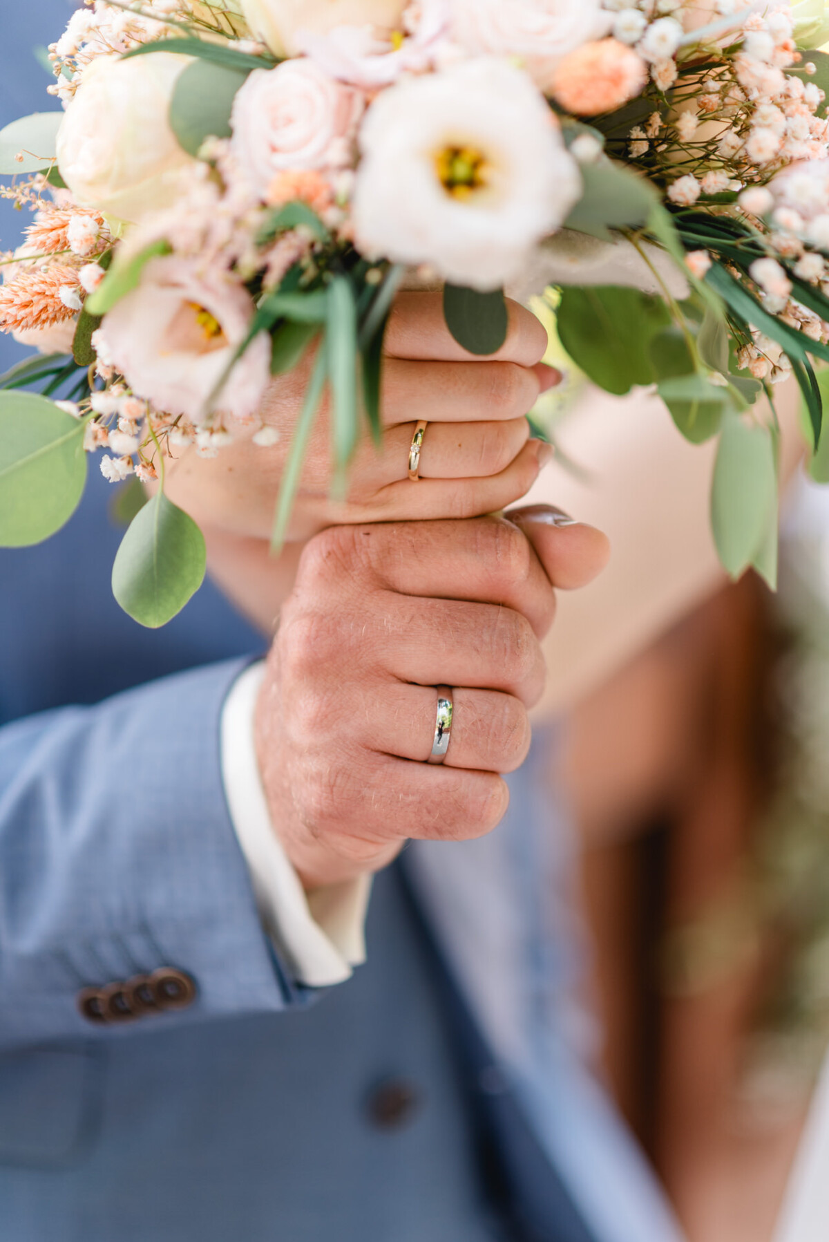 Eine Braut und ein Bräutigam halten einen Blumenstrauß in der Hand.