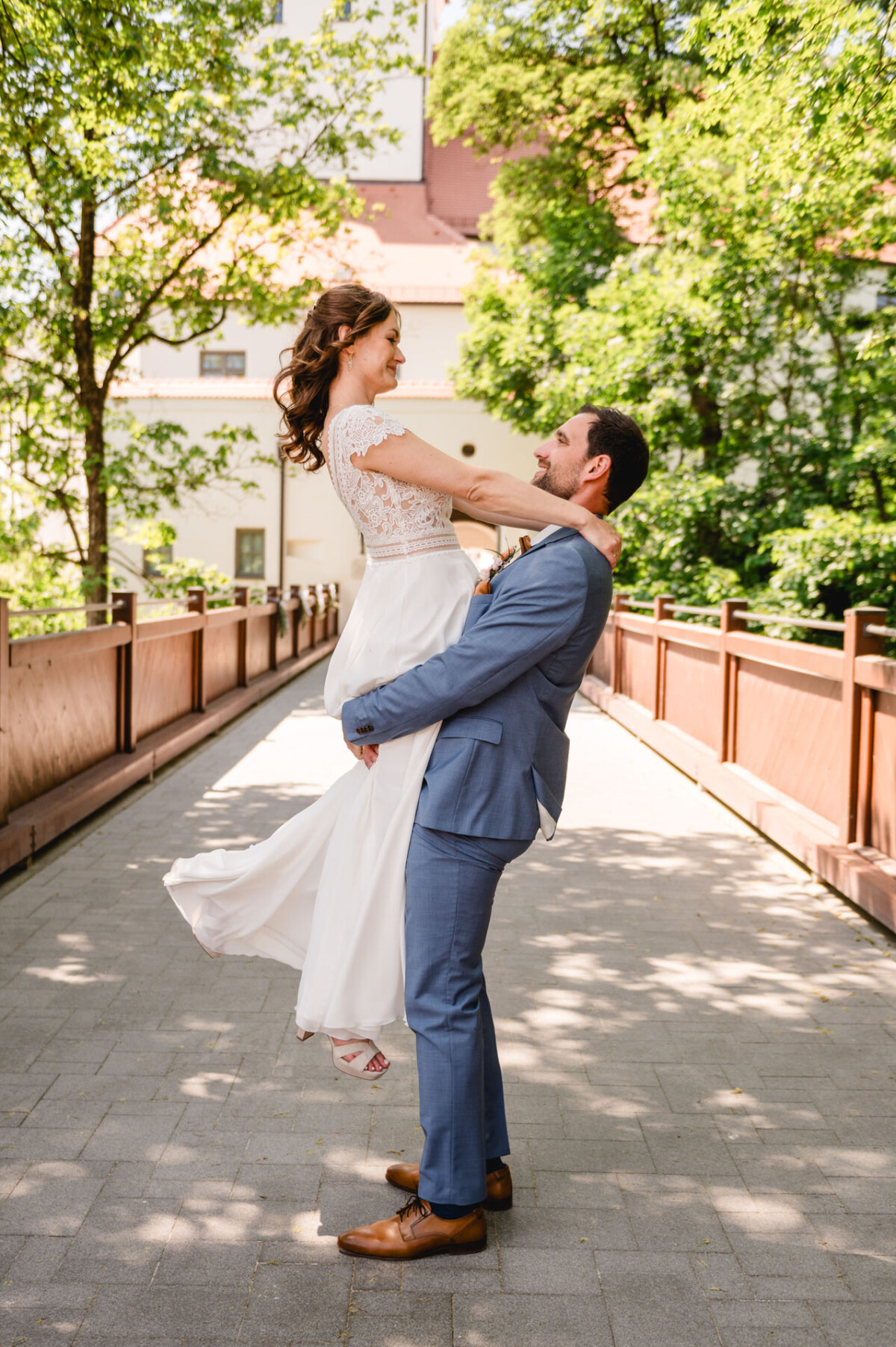 Eine Braut und ein Bräutigam halten sich gegenseitig auf einer Brücke.