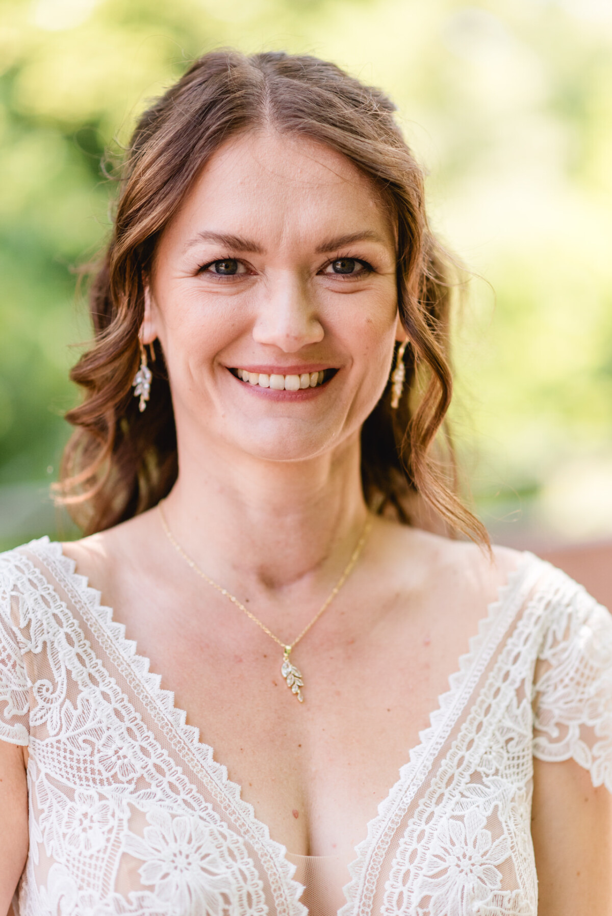 Eine Frau in einem weißen Hochzeitskleid lächelt in die Kamera.