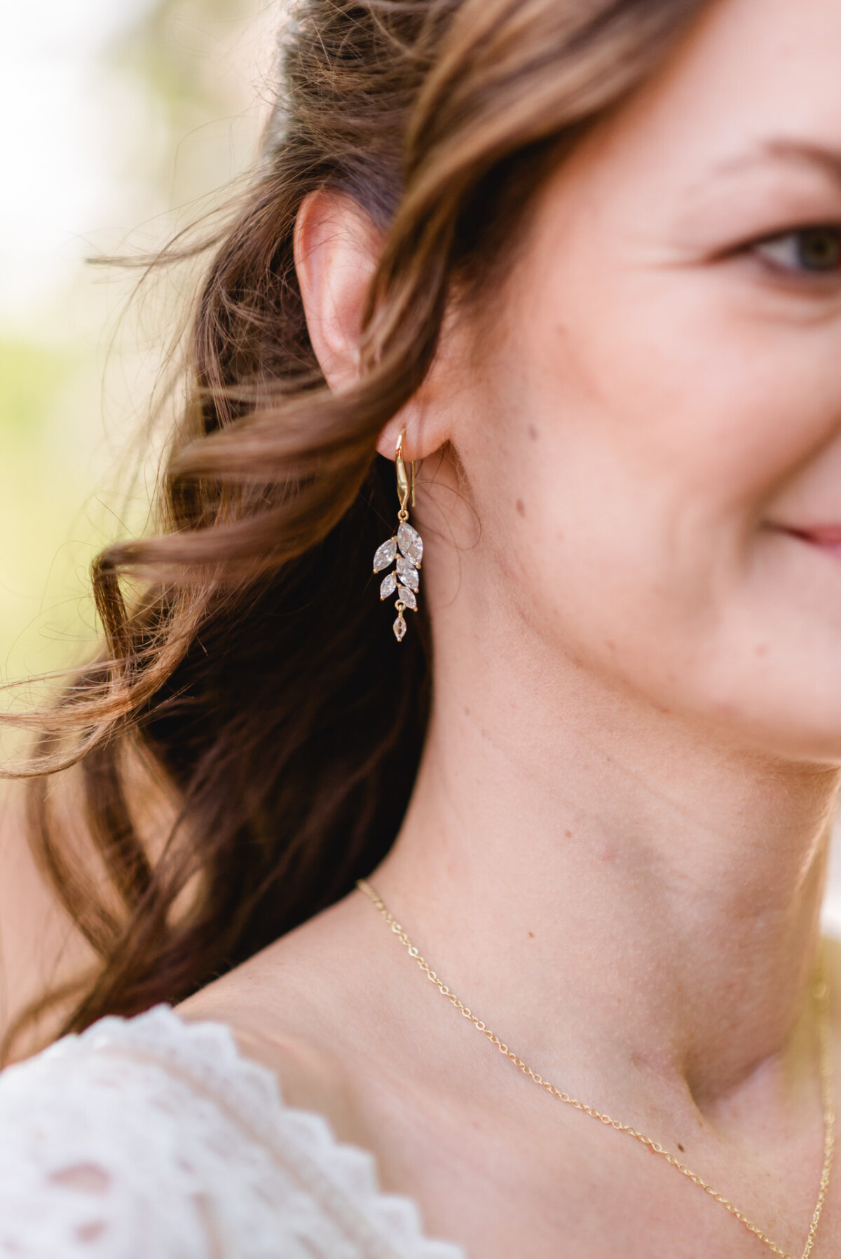 Eine Frau trägt ein weißes Kleid und goldene Ohrringe.
