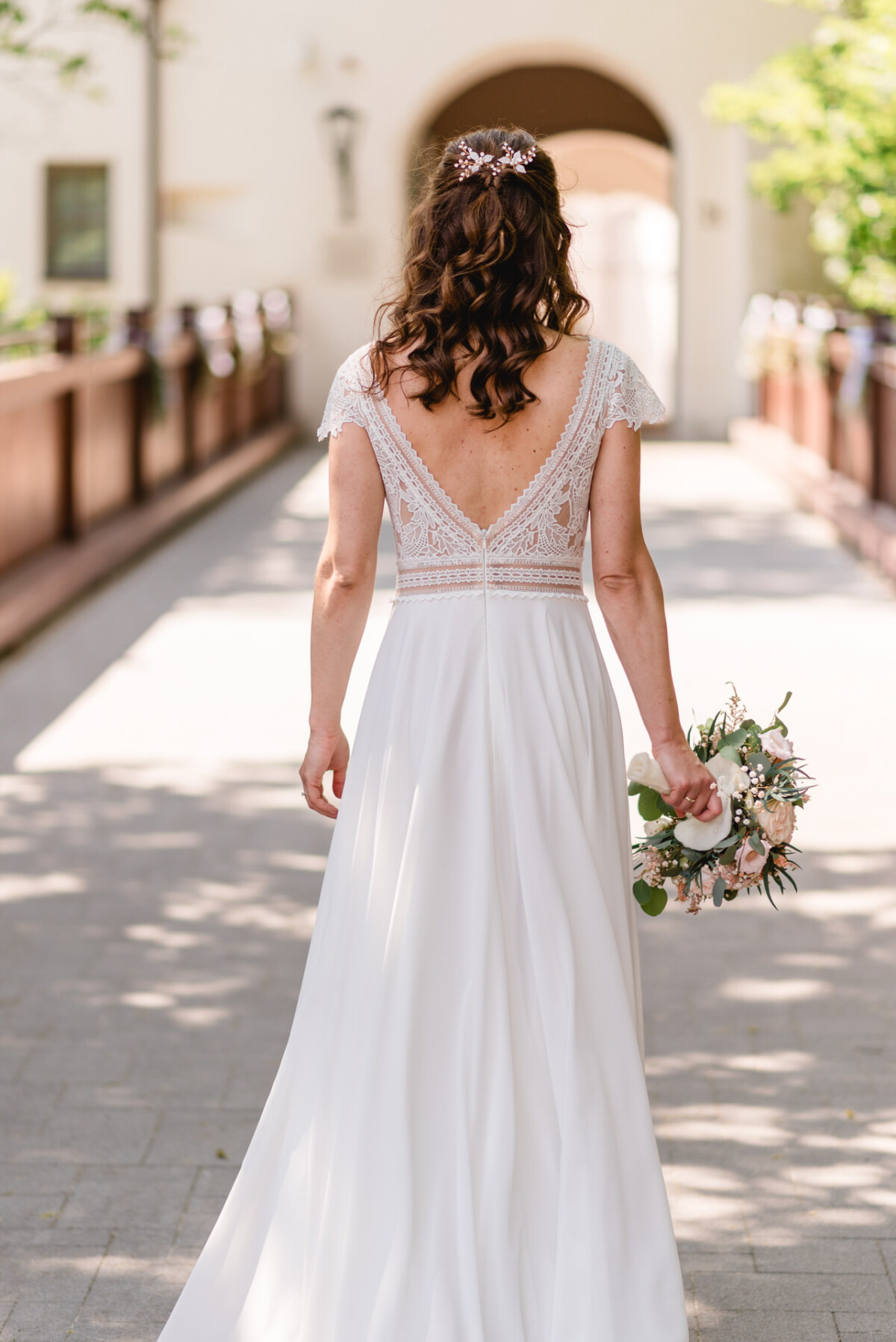 Eine Braut in einem weißen Hochzeitskleid geht einen Weg entlang.