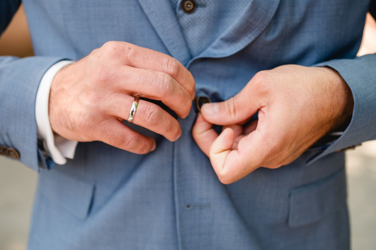 Ein Mann steckt seinen Ehering an seine Jacke.