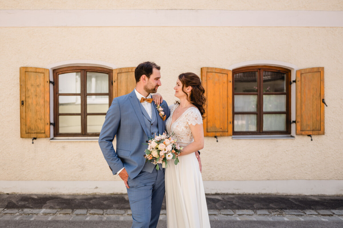 Eine Braut und ein Bräutigam stehen vor einem Gebäude.