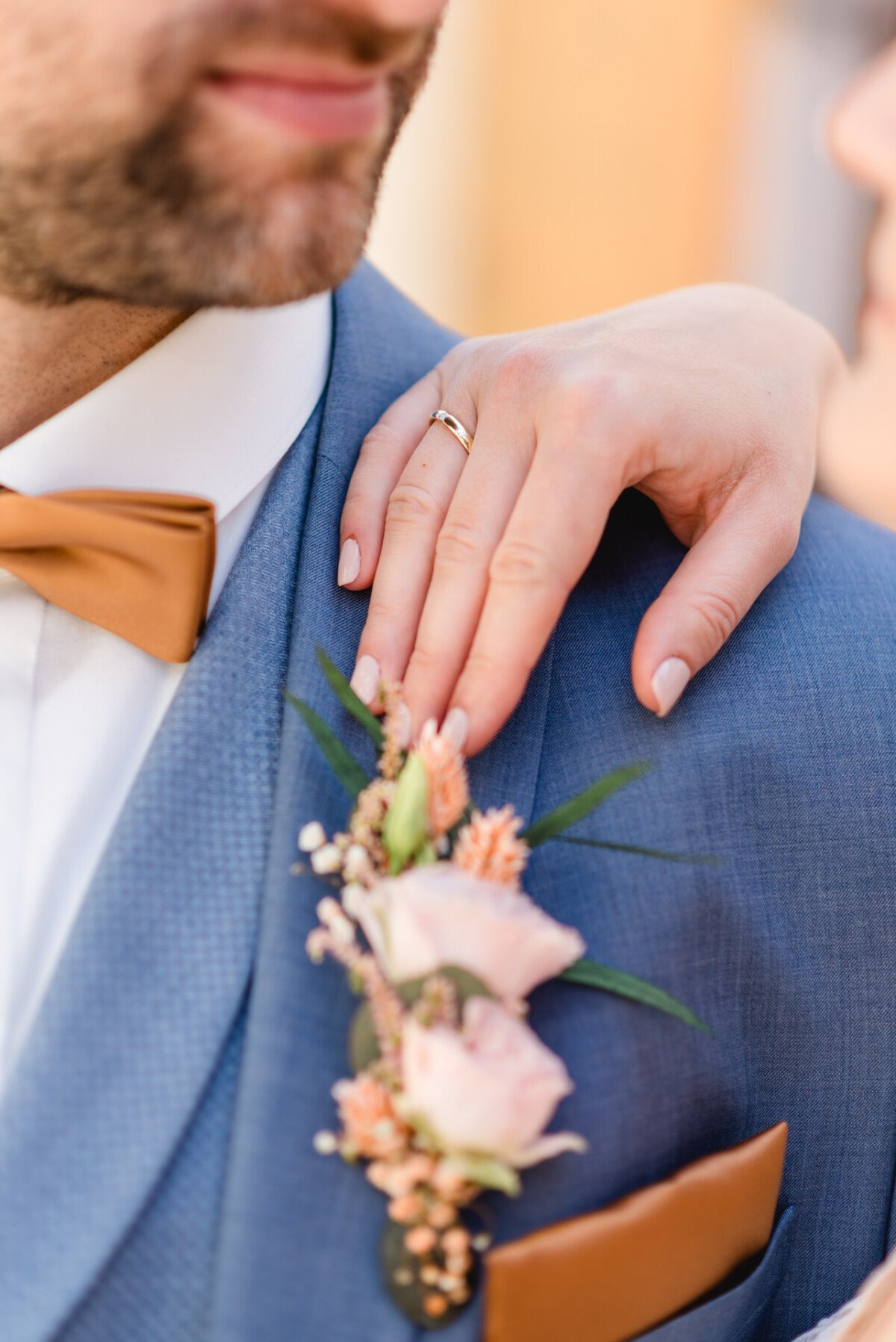 Eine Braut und ein Bräutigam mit einer Ansteckblume an den Händen.