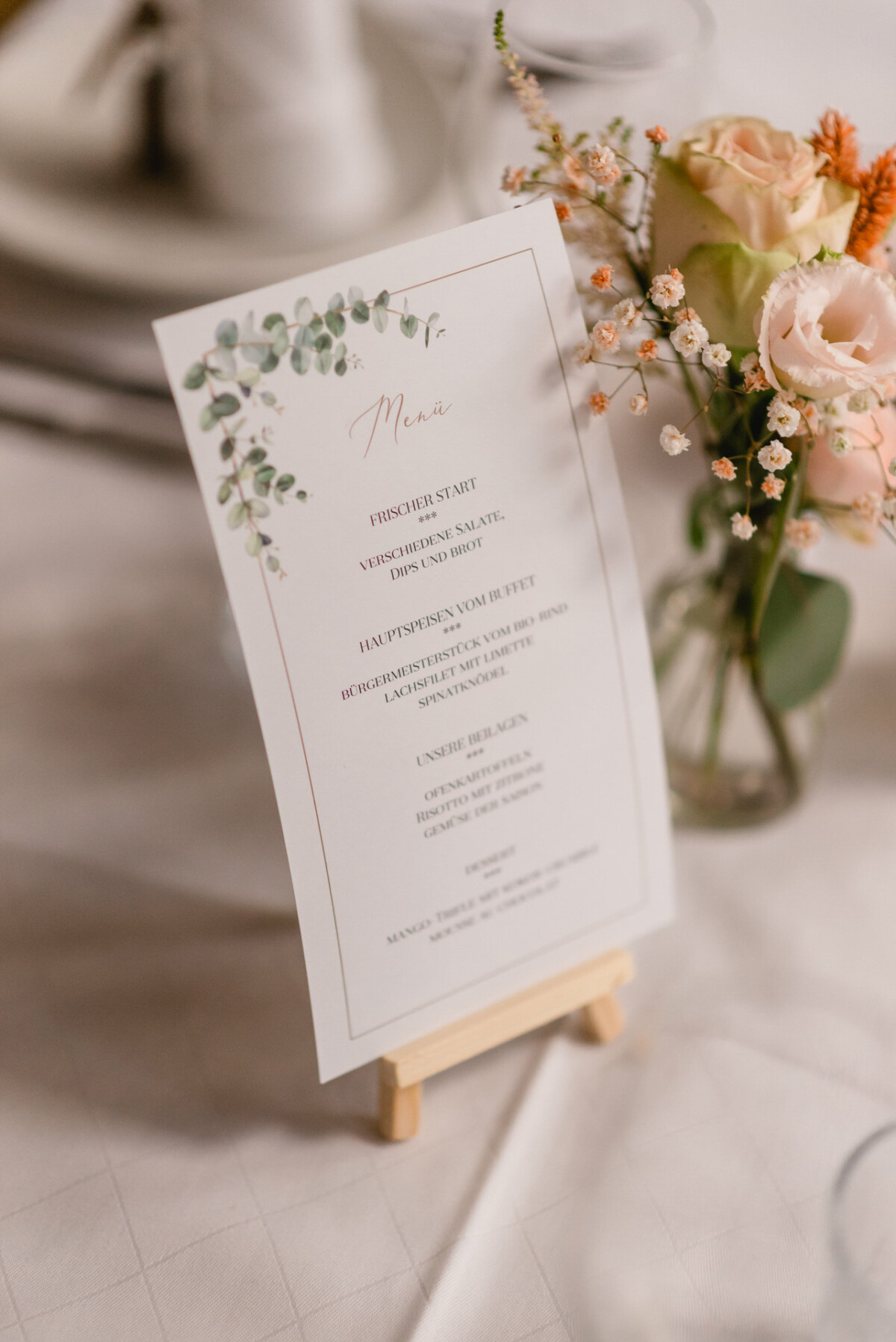 Ein gedeckter Tisch mit Menü und Blumen.
