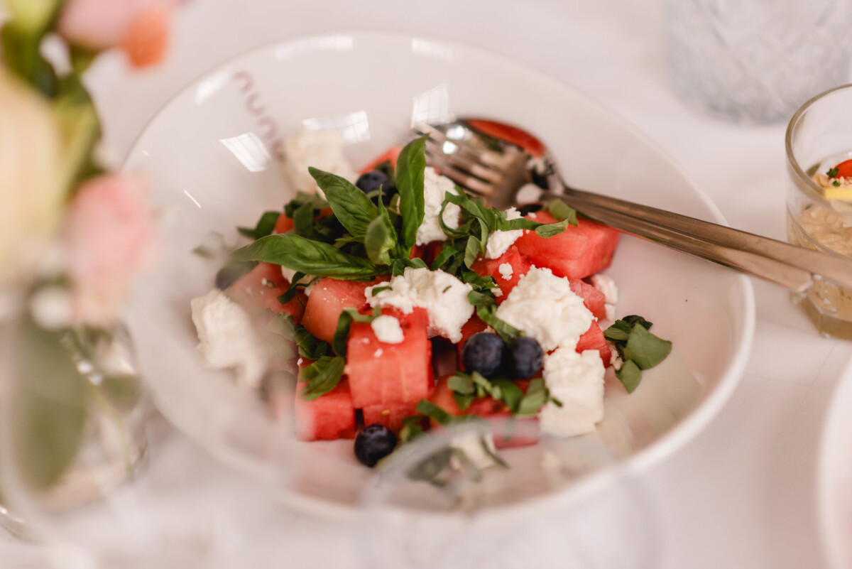 Ein Wassermelonensalat mit Feta und Blaubeeren auf einem Tisch.
