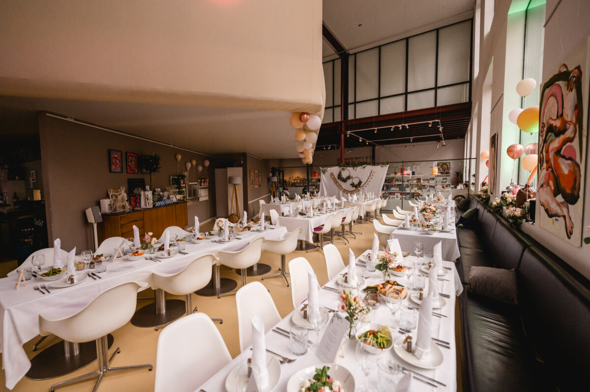 Ein Raum mit Tischen und Stühlen für eine Hochzeitsfeier.