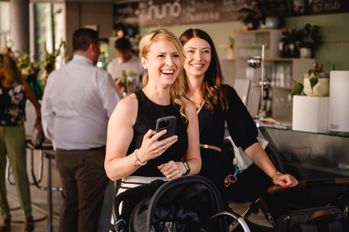 Zwei Frauen stehen mit einem Baby im Kinderwagen in einem Restaurant.