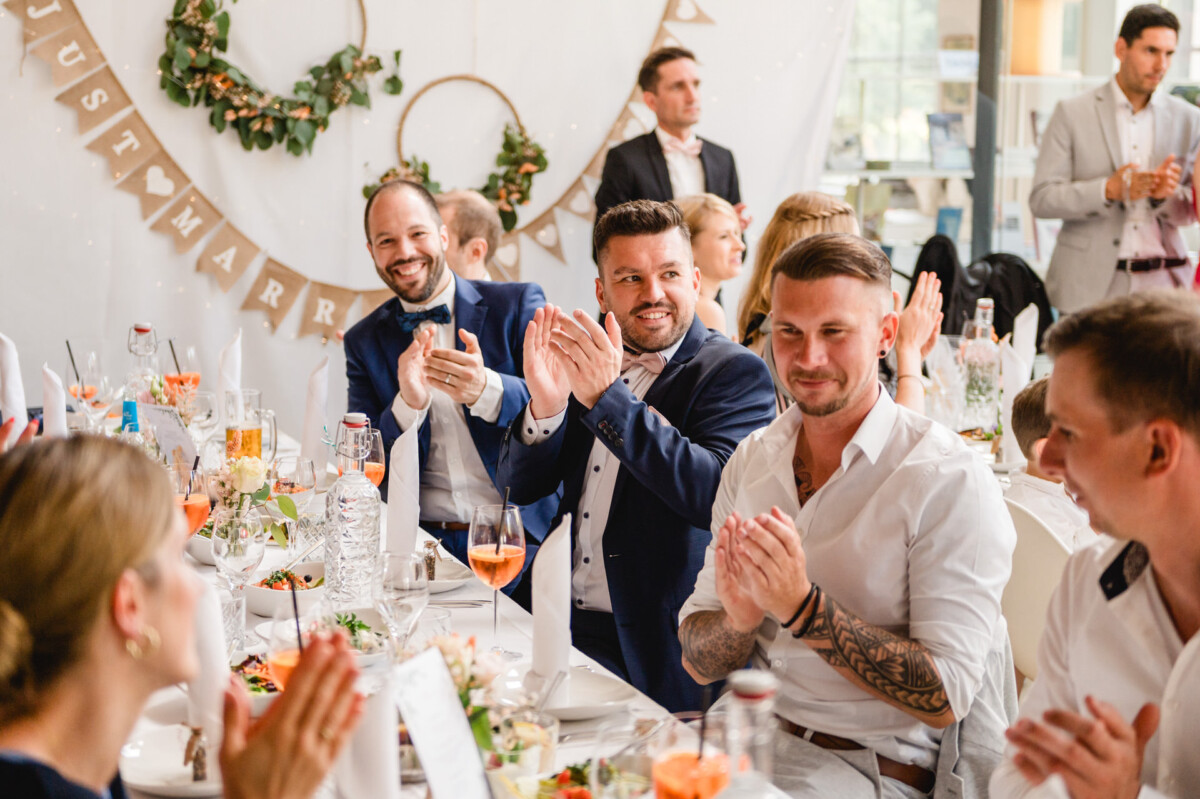 Eine Gruppe von Menschen klatscht bei einer Hochzeitsfeier.