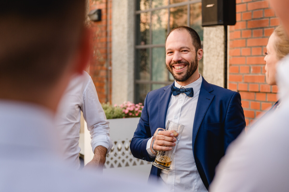 Ein Mann in Anzug und Fliege trinkt ein Bier.