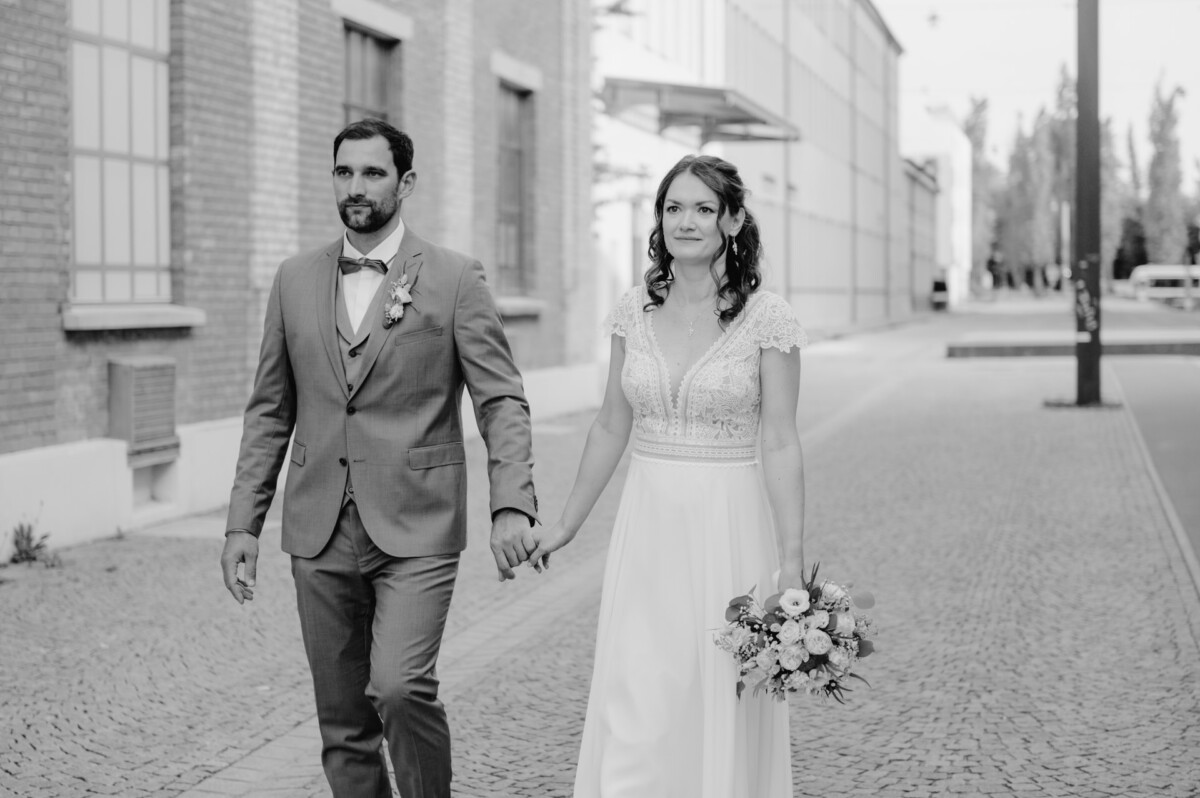 Schwarz-Weiß-Foto von Braut und Bräutigam, die die Straße entlang gehen.