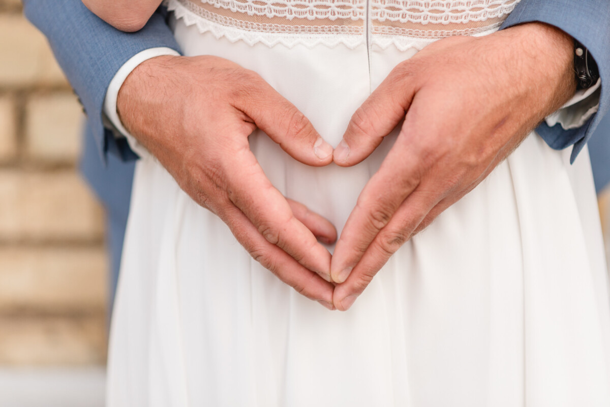 Ein Brautpaar formt mit seinen Händen ein Herz.