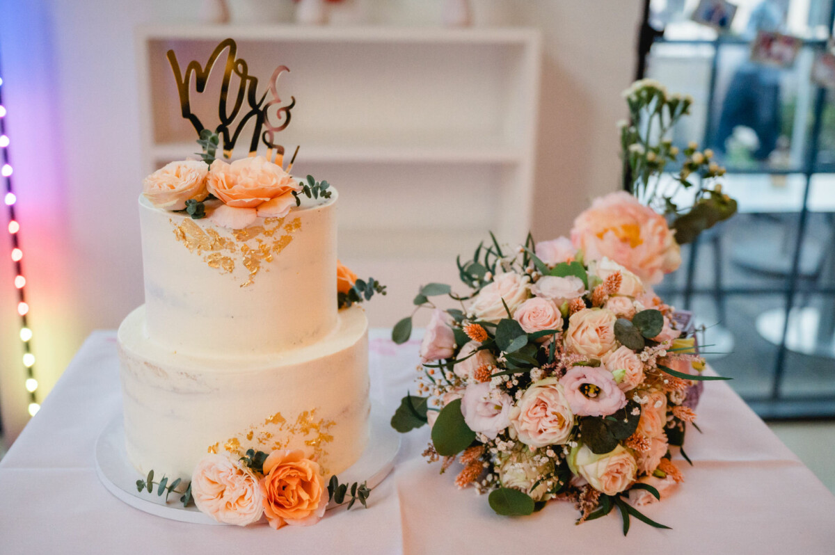 Eine Hochzeitstorte und Blumen auf einem Tisch.