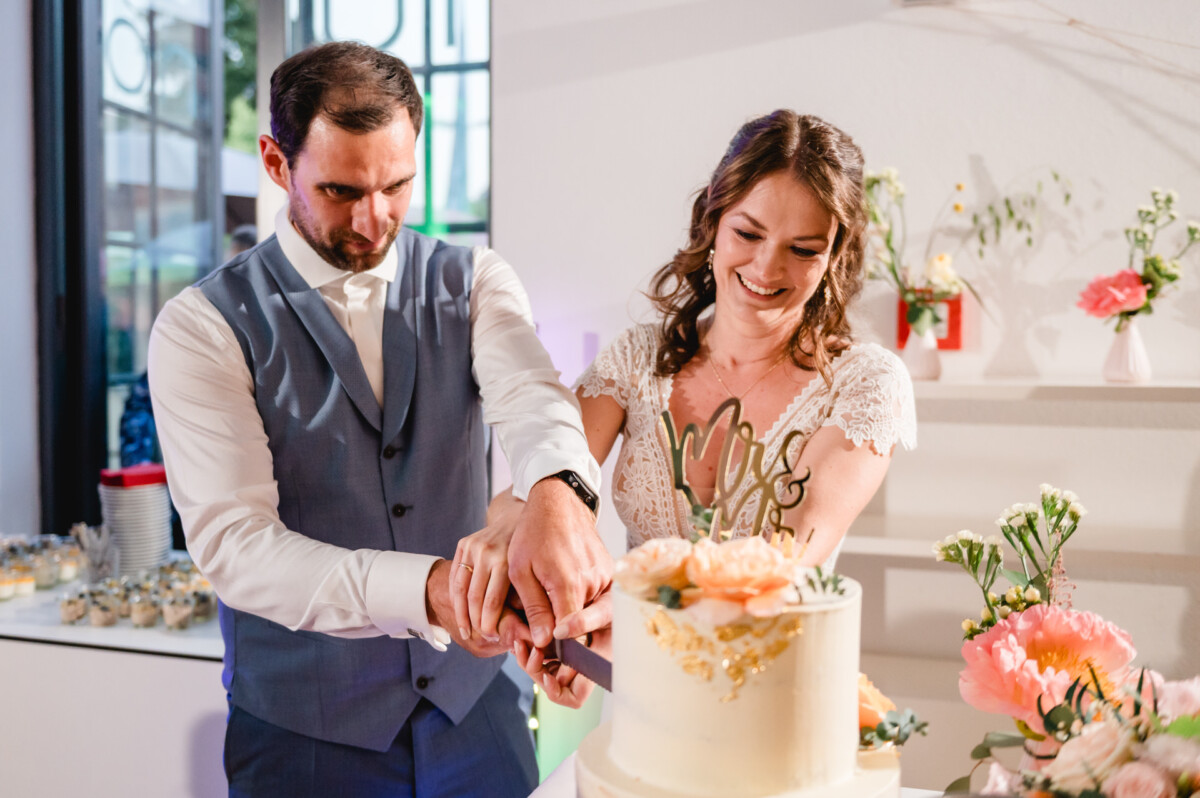 Eine Braut und ein Bräutigam schneiden ihre Hochzeitstorte an.
