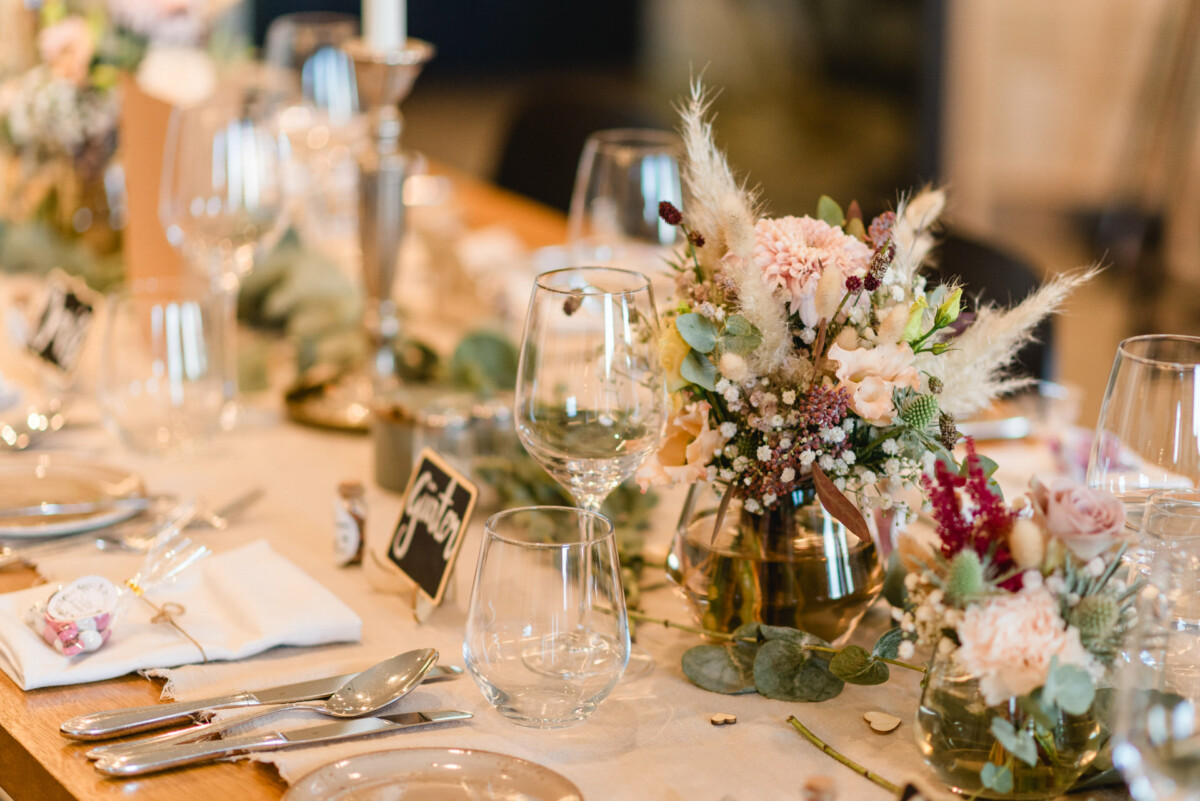 christian-lorenz.net Elegant gedeckter Esstisch mit Blumenschmuck, Gläsern und Kerzen. Neutrale Töne und sanfte Beleuchtung schaffen eine gemütliche Atmosphäre.