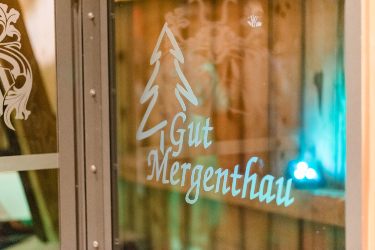 Glastür mit dem Schriftzug „Gut Mergenthau“ und einem Baummotiv.