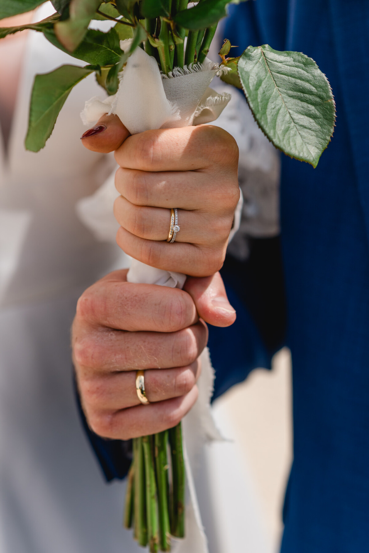 Ein Paar hält gemeinsam einen Blumenstrauß in den Händen und zeigt dabei seine Eheringe.