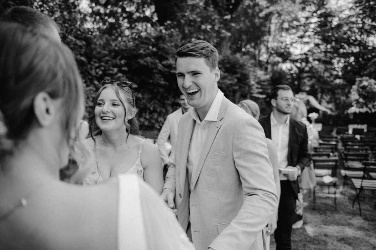 Eine Gruppe von Menschen in formeller Kleidung unterhält sich im Freien und lacht bei einem Treffen.