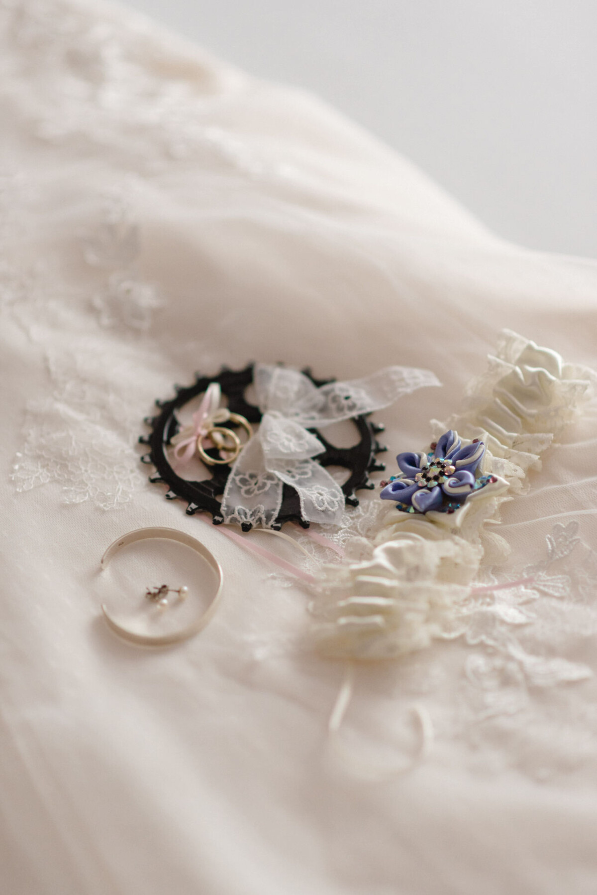 Hochzeitsaccessoires aus Spitzenstoff: eine Schleife aus Band, Eheringe, eine florale Haarnadel und ein Strumpfband.