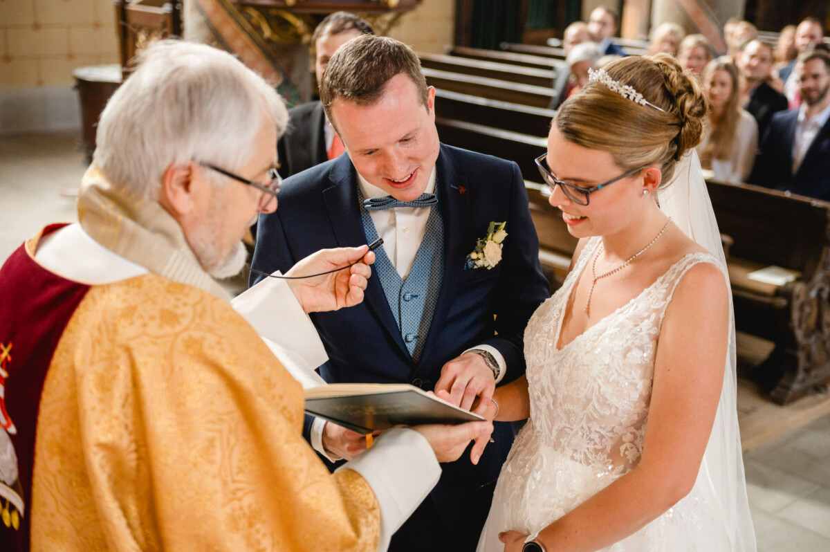 Ein Paar tauscht während einer von einem Priester in einer Kirche durchgeführten Hochzeitszeremonie Ringe aus.