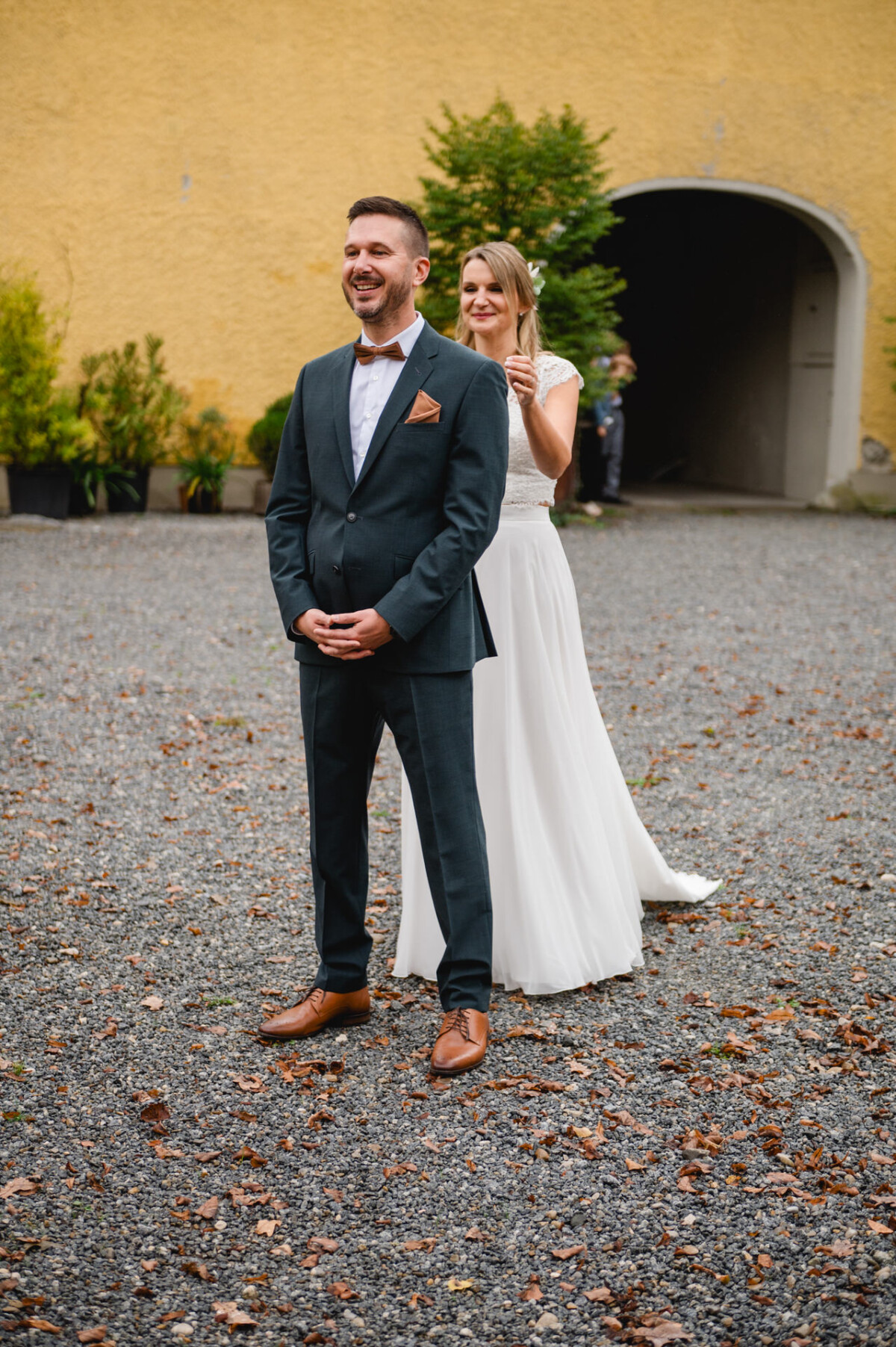 Eine Braut bereitet sich darauf vor, den Bräutigam beim ersten Blick im Freien von hinten zu überraschen.