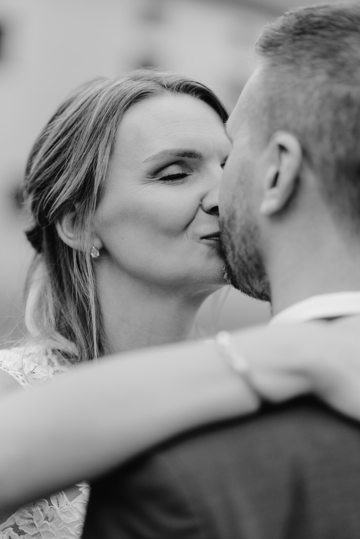 Ein Schwarzweißfoto eines Paares, das sich eng umarmt und zu küssen scheint. Der Fokus liegt auf dem Gesicht der Frau.