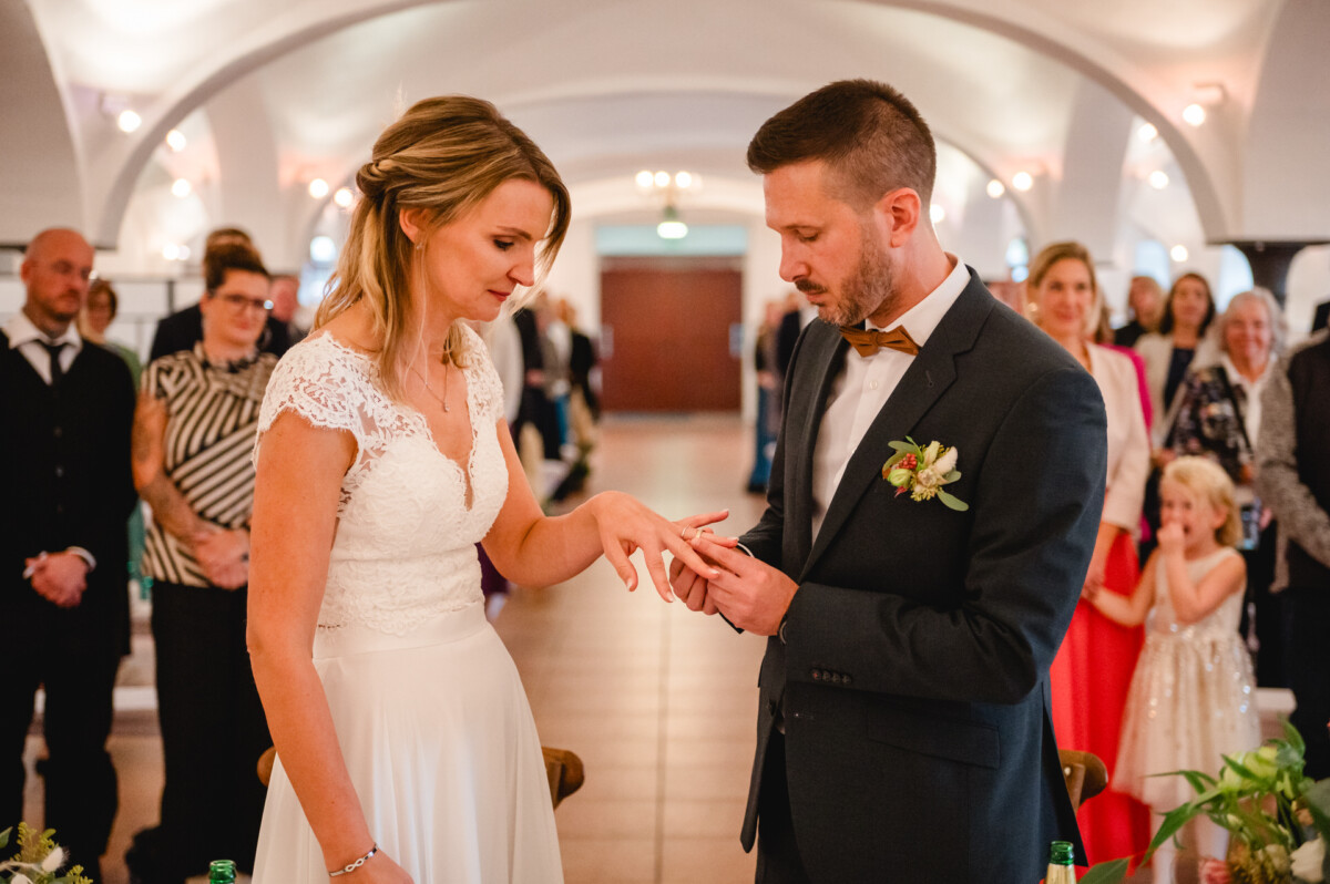 Braut und Bräutigam tauschen während einer Hochzeitszeremonie in einem mit Gästen gefüllten Raum Ringe aus.