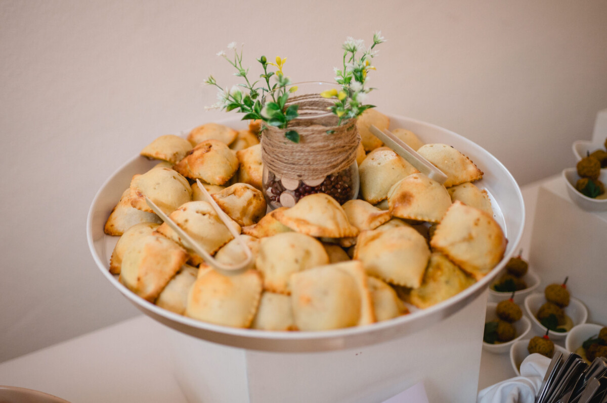Ein großer Teller gefüllt mit gebackenem Gebäck, dazu ein kleines Gefäß mit dekorativen Blumen in der Mitte.