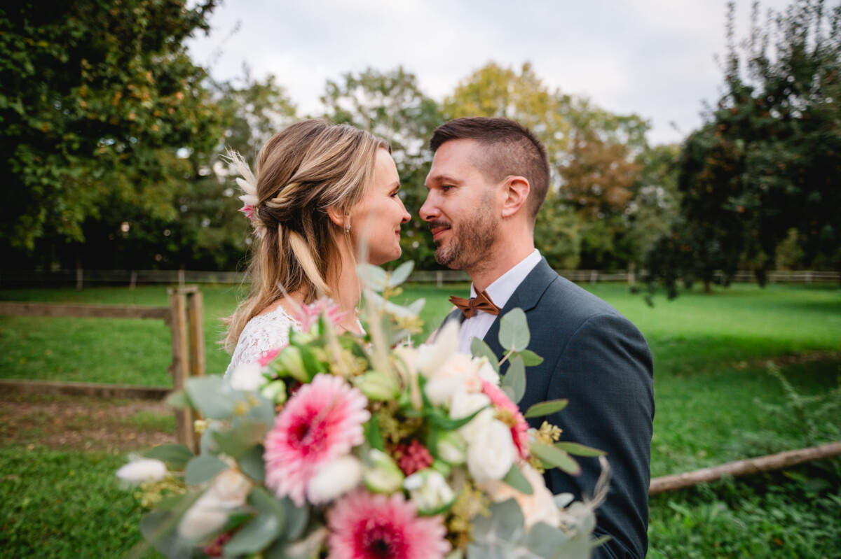 Ein Paar steht eng beieinander im Freien, einander zugewandt, im Vordergrund ein Blumenstrauß.
