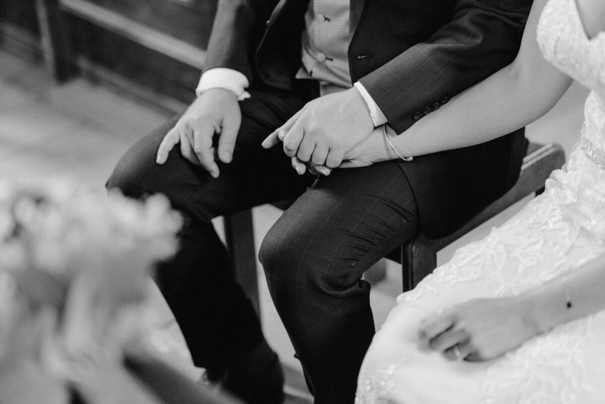 christian-lorenz.net Ein Paar in Abendgarderobe sitzt Händchen haltend da. Nur Unterkörper und Hände sind sichtbar. Das Bild ist schwarz-weiß.