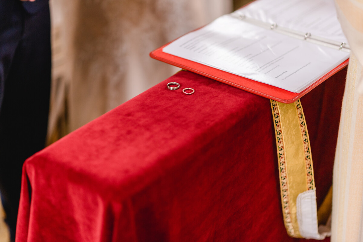 christian-lorenz.net Zwei Eheringe liegen auf einem Altartuch aus rotem Samt, daneben liegt ein offener Ordner mit Papieren.