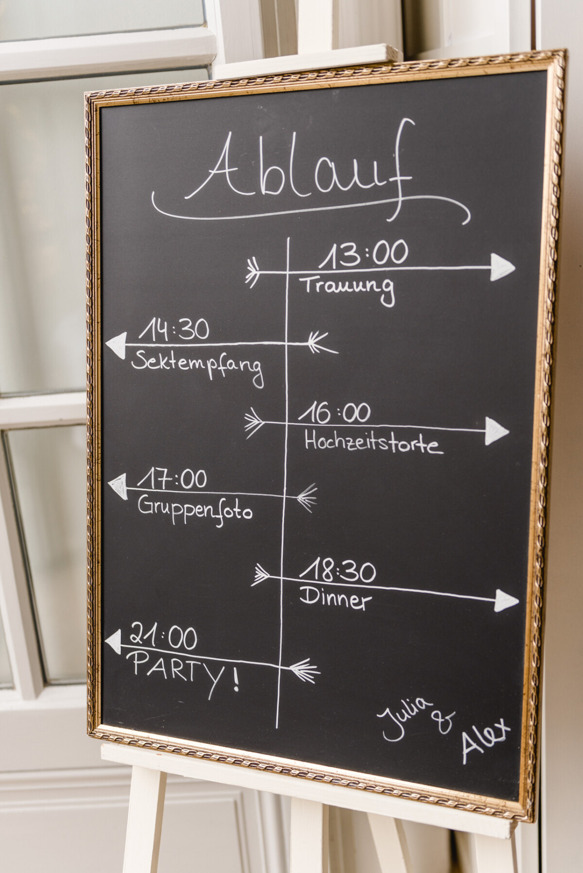 christian-lorenz.net Tafel-Hochzeitsplan mit Veranstaltungen: 13:00 Trauung, 14:30 Sektempfang, 16:00 Hochzeitstorte, 17:00 Gruppenfoto, 18:30 Abendessen, 21:00 Party. Verziert mit den Namen Julia und Alex.