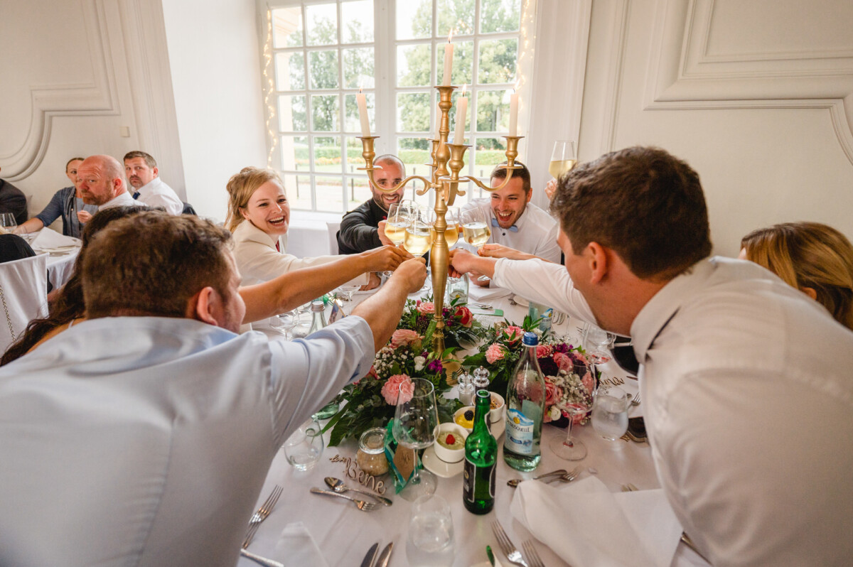 christian-lorenz.net Menschen, die um einen dekorierten Tisch in der Nähe eines großen Fensters sitzen, stoßen mit Gläsern an.