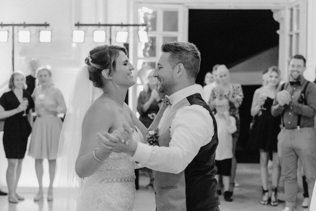 christian-lorenz.net Braut und Bräutigam tanzen gemeinsam auf ihrer Hochzeitsfeier. Im Hintergrund schauen die Gäste zu und klatschen.