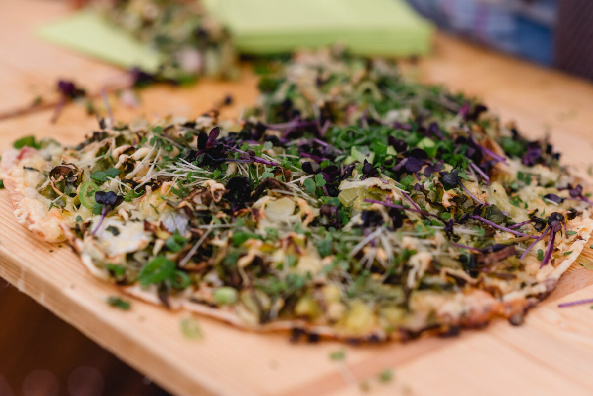 christian-lorenz.net Eine Pizza mit dünnem Boden und verschiedenen Blattsalaten und Gemüse auf einem Holzbrett.