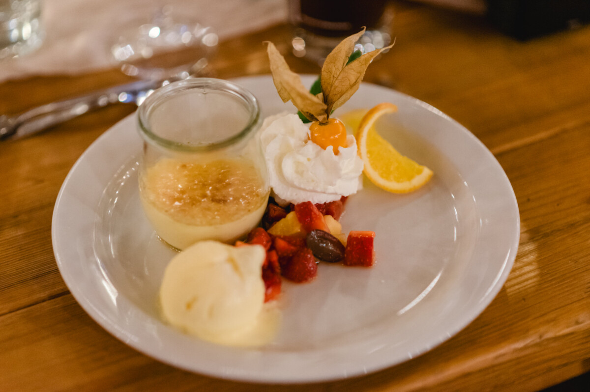 Dessertteller bei der Hochzeit im Schammenhof, Langenau, mit einem Glas Vanillesoße, einer Kugel Eis, Schlagsahne mit Fruchtgarnitur, einer Orangenscheibe und gemischten Fruchtstücken auf einem Holztisch. Dessertteller bei der Hochzeit im Schammenhof, Langenau, mit einem Glas Vanillesoße, einer Kugel Eis, Schlagsahne mit Fruchtgarnitur, einer Orangenscheibe und gemischten Fruchtstücken auf einem Holztisch.